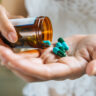 woman s hand pours medicine pills out bottle 1