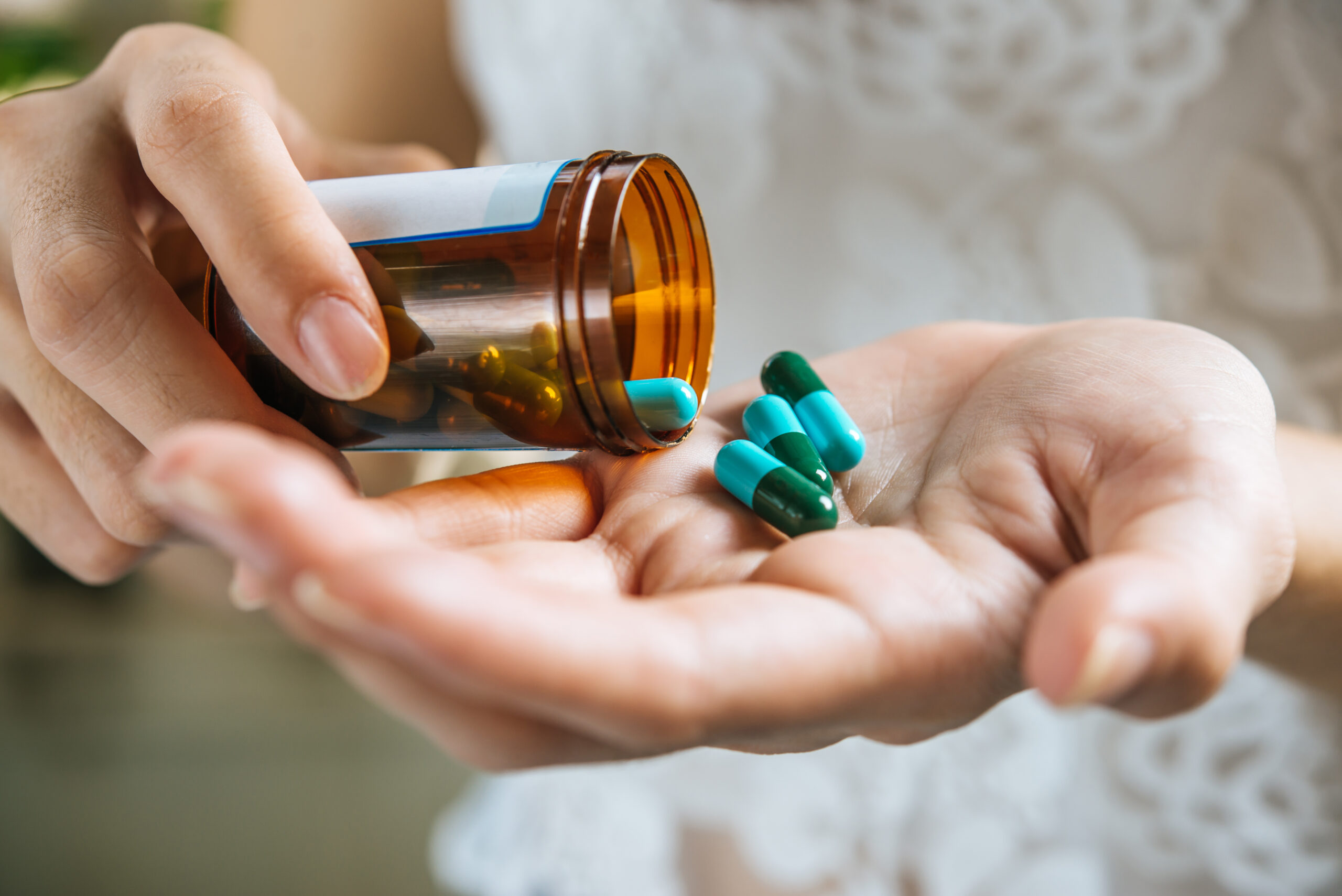 woman s hand pours medicine pills out bottle 1 scaled